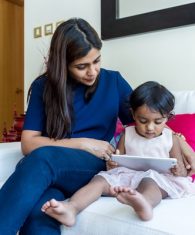 Little girl reading e book on tablet with her mother